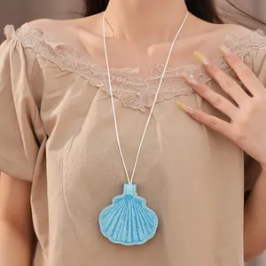 Close-up of a blue leather shell eyeglass holder necklace worn on a lace top.