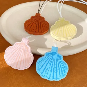 Detailed view of colorful leather seashell charms in pink, blue, yellow, and brown