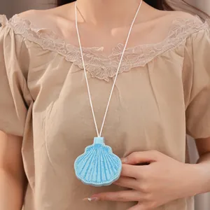 Close-up of light blue leather seashell glasses clip necklace worn on beige top.