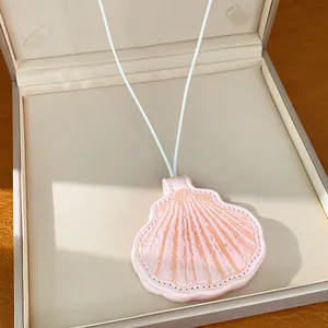 Close-up of a stylish pink leather shell pendant necklace presented in a beige luxury gift box.