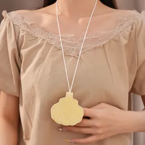 Detailed macro view of a yellow shell-shaped leather pendant necklace on a beige blouse