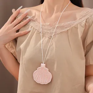 Close-up detail of a stylish pink leather shell-shaped eyewear clip necklace on a model
