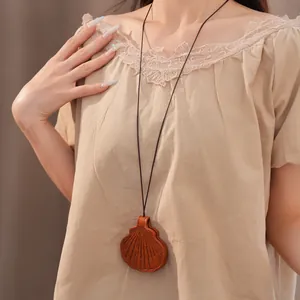 Close-up of a brown leather shell pendant necklace worn on a light beige lace blouse