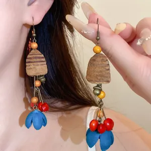 Nahaufnahme von ethnischen Holz-Ohrhängern mit blauen Stoffblüten in Retro-Design