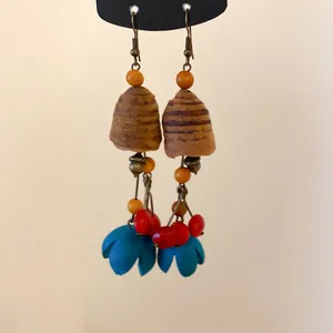 Makroaufnahme ethnischer Holzohrringe mit farbenfrohen Samen und blauen Blumentasten