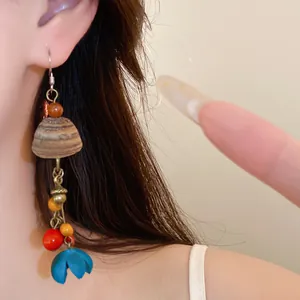 Nahaufnahme von Vintage-Ohrringen im Ethno-Stil mit Holzperlen und blauer Blume