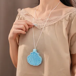 Close-up detail of a stylish blue leather shell pendant necklace on a white cord.