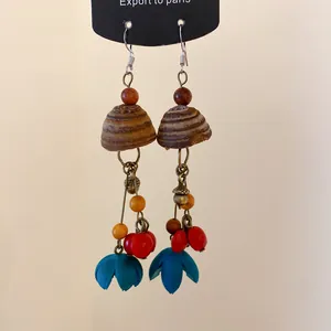 Detailansicht der ethnischen Vintage Holz-Quastenohrringe mit roten Samen und blauen Blüten.