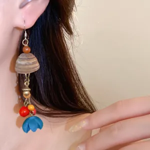 Nahaufnahme eines ethnischen Ohrrings mit Holzperlen und blauem Tulpenanhänger