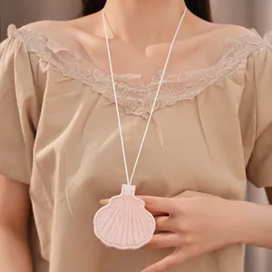 Close-up detail of an elegant light pink leather seashell pendant necklace worn by a model