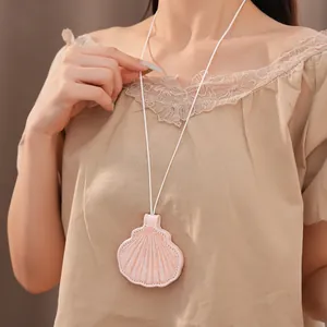 Close-up of a shell-shaped leather necklace accessory worn on a beige lace blouse