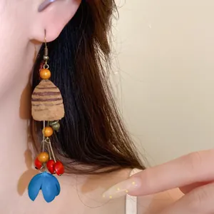 Detaillierte Nahaufnahme von Vintage-Holzohrringen mit blauer Quaste an einem Model
