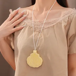 Close-up detail of a yellow shell-shaped leather pendant necklace worn with a beige lace top