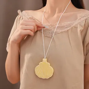 Close-up of a yellow shell-shaped leather glasses holder necklace worn by a model