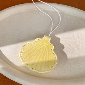 Macro view of a stylish yellow shell-shaped leather pendant with intricate stitching details