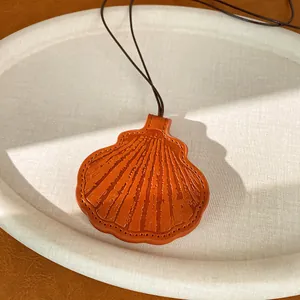 Detailed macro view of a shell-shaped leather pendant showing fine embossed texture
