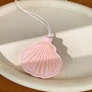 Detailed close-up view of a pink leather shell pendant with intricate stitching and white cord