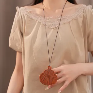 Close-up view of a shell-shaped leather eyewear holder necklace worn on a long black cord