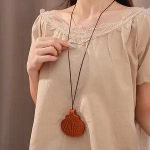Close-up detail of a long fashion necklace with brown leather shell glasses holder pendant