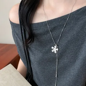 Élégant collier à pendentif fleur argenté porté par un mannequin dans un haut gris