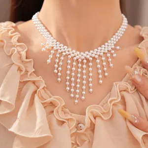 Detalle de un elegante collar de flecos con perlas blancas usado por una modelo mujer