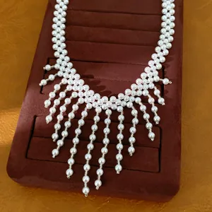 Vista detallada de un elegante collar de perlas redondas con flecos estilo palacio