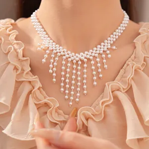 Detalle de un elegante collar de perlas blancas con flecos llevado por una modelo