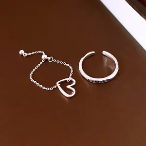 Detailed view of minimalist silver heart chain ring and adjustable engraved ring set