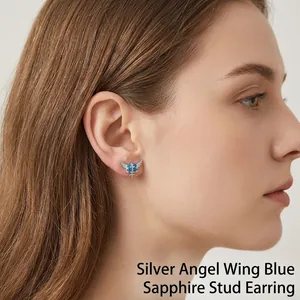 Elegante pendiente de botón con alas de estrella, corazón y cruz, gemas azules y titanio