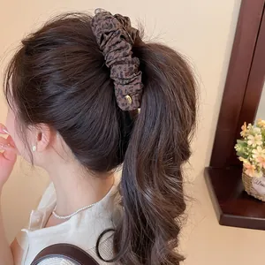 Detailopname van vintage bananenclip met luipaardprint en mesh op een hoge paardenstaart.