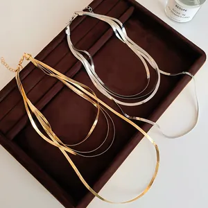 Gros plan élégant de colliers à chaînes serpent dorées et argentées sur plateau velours.