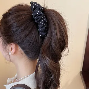 Close-up van een retro zwarte banaan haarclip met polkadots voor een paardenstaart.