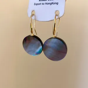 Nahaufnahme von minimalistischen runden dunklen Muschelohrringen mit goldenen Haken