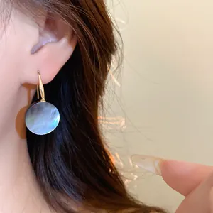 Elegante runde schillernde Muschel-Ohrhänger an einem Modell für einen minimalistischen Stil