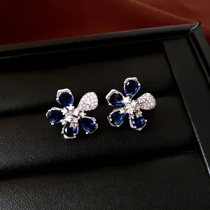 Elegantes pendientes de flores de circón azul y blanco en un estuche de joyas negro