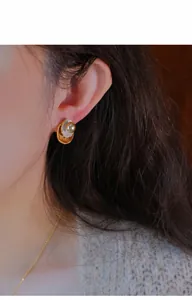Close-up van vintage pareloorknopje gedragen op het oor met gouden drop-olie design