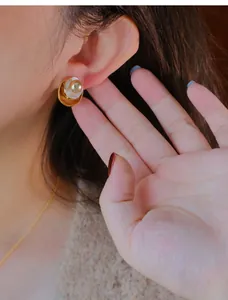 Macro weergave van vintage parel oorknopjes met een gouden emaille afwerking op model