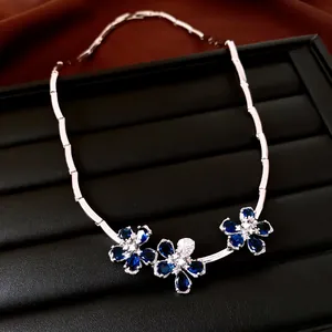 Detalle de un collar de plata con tres colgantes de flores de circón azul en bandeja