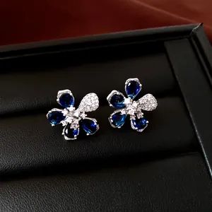 Primer plano de pendientes de flores con circonitas azules y blancas en caja negra