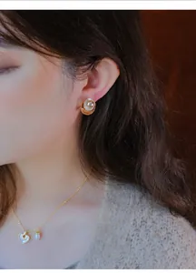 Detailopname van retro gouden pareloorbellen met cirkelvormig emaille effect op het oor.