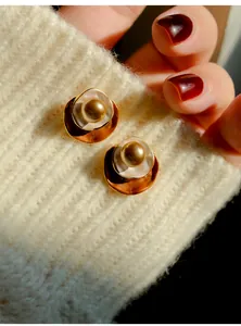 Macrodetail van vintage pareloorbellen in Maillard-stijl op een crème gebreide trui