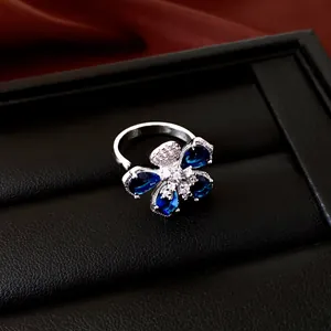 Primer plano de un elegante anillo de flores con piedras azul zafiro y circonitas