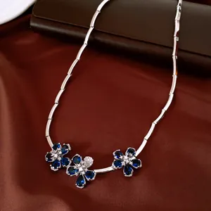 Vista detallada de un collar plateado con elegantes colgantes de flores de circón azul