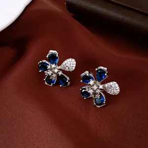 Primer plano de elegantes pendientes de flor con pétalos de circonita azul intenso