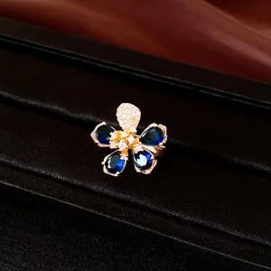 Elegant gold plated flower ring featuring deep blue teardrop zircons and white crystals