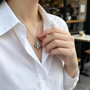 Gros plan détaillé d'un collier cactus argenté porté par une femme en chemise blanche.