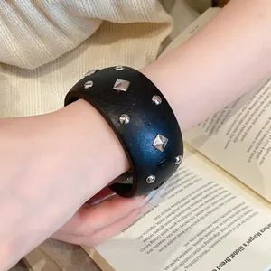 Detailaufnahme eines schwarzen breiten Vintage-Armbands mit silbernen Nieten am Handgelenk