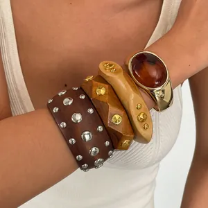 Nahaufnahme von Vintage-Harz- und Holzarmbändern mit Gold- und Silbermetallnieten.