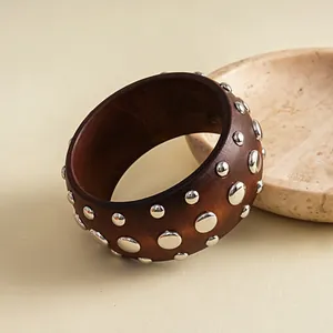 Nahaufnahme eines Vintage-Harzarmreifens in Braun mit polierten silbernen Metallnieten