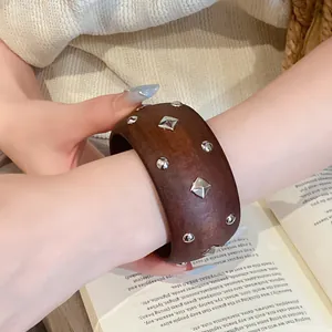 Detailansicht eines braunen Holzarmbands mit silbernen geometrischen Nieten am Arm